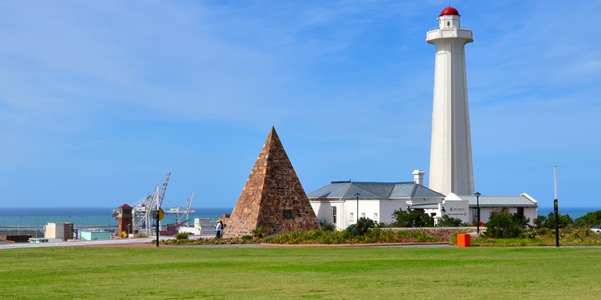 Donkin Reserve with a white lighthouse with a red top, stone pyramid, grassy area, and buildings.