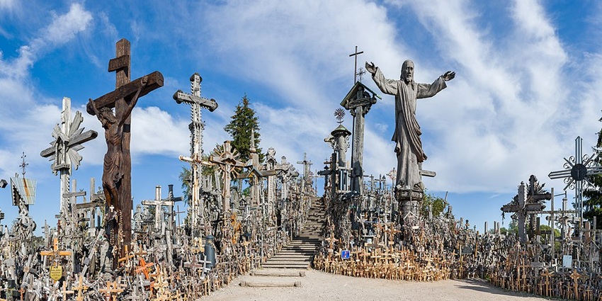 Thousands of crosses are standing on a hill in Šiauliai, Lithuania, under a blue sky.