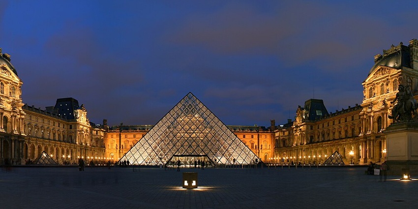An external photographic view of the spectacular Louvre Museum in France at night.