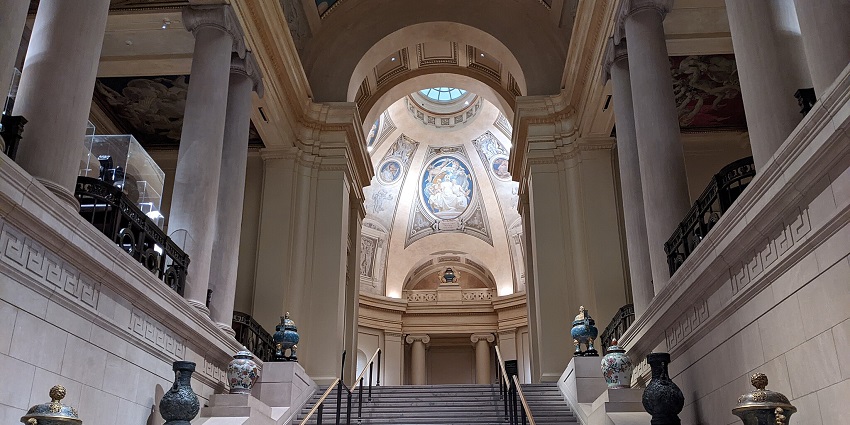 A lavish staircase with ancient vases displayed at a top museum, The Museum of Fine Arts.