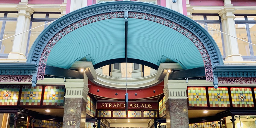 Strand Arcade entrance, ornate Victorian design, colorful stained glass, people entering.