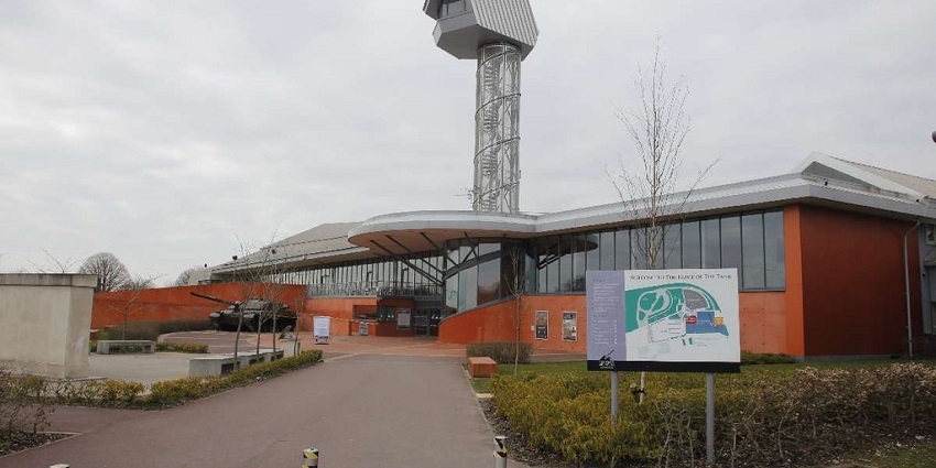 Museum building with a tall observation tower and a tank displayed near the entrance.