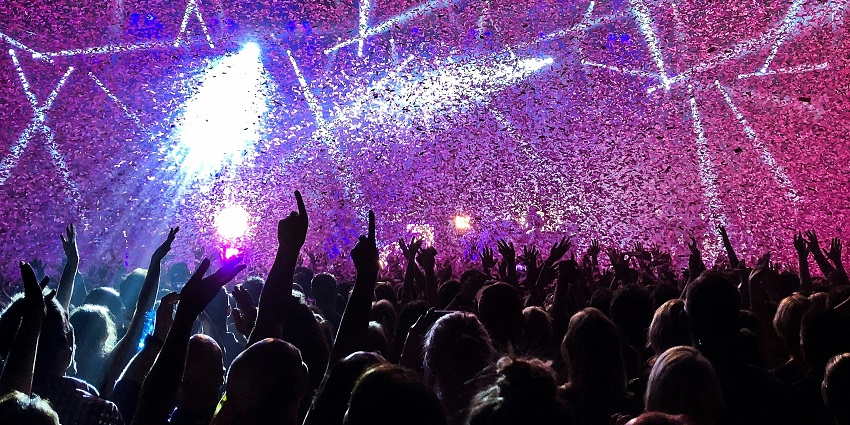 A lively crowd enjoying drinks and DJ music at The Wave Bar, with confetti all around