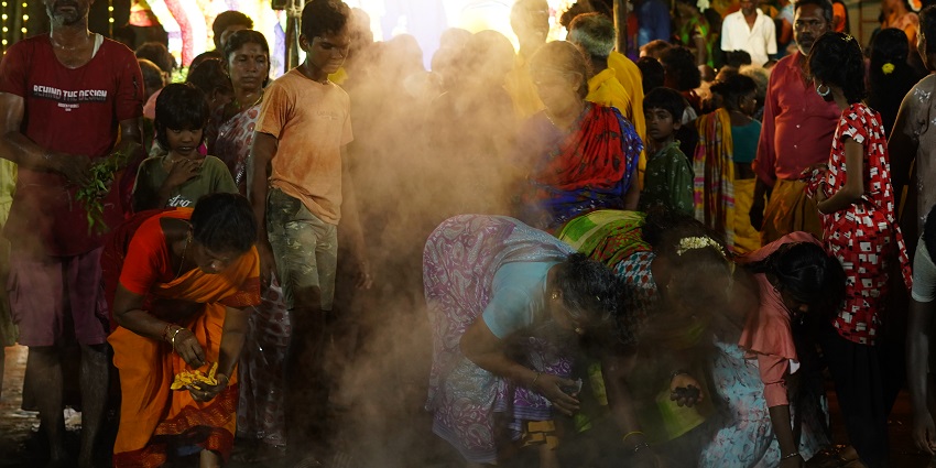 An Image of people celebrating the Thimithi festival in Puducherry, with smoke rising from below.