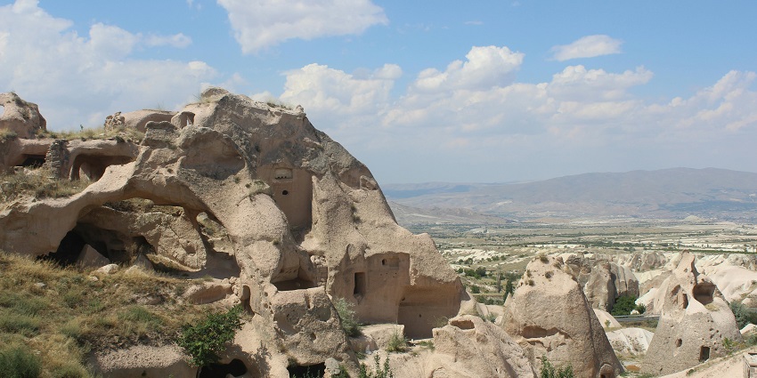 An image of visitors climbing to the top of Uchisar Castle to enjoy panoramic views of Cappadocia.
