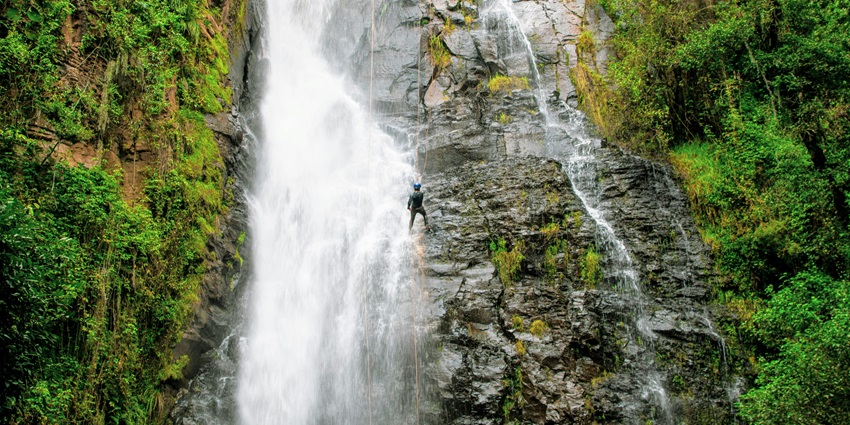 An adventurer scaling a steep, rugged cliff of Black rock waterfalls