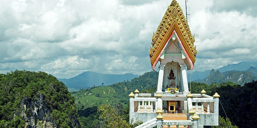 An image showing Tiger Cave Temple, the best place near Krabi, with a statue and surrounding hills.
