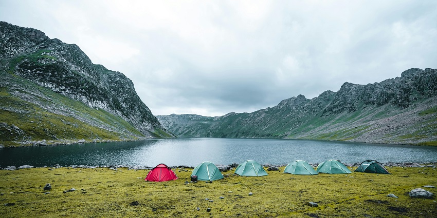 Distant view of tents by the lake and majestic mountains in the background