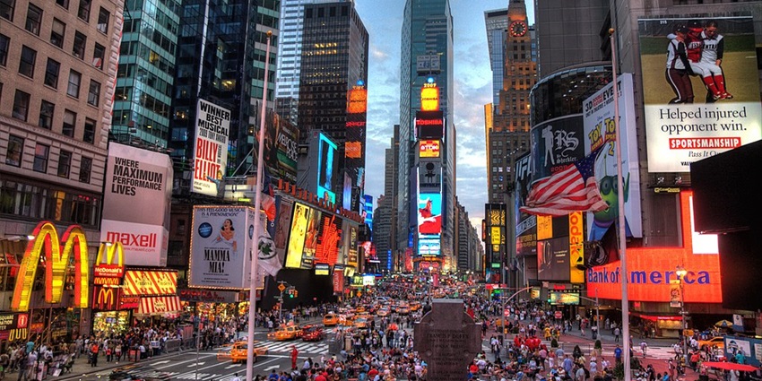 A crowd-packed Times Square of New York City with bustling traffic and numerous billboards.