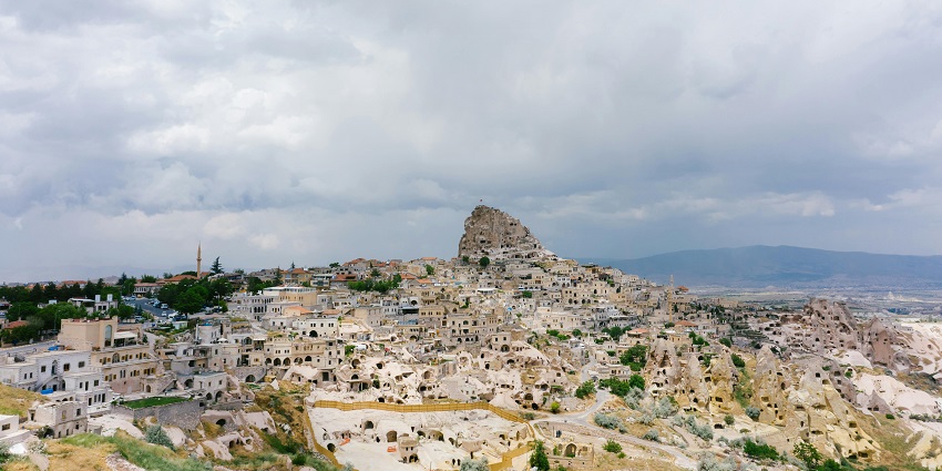 An image of visitors strolling along the pathways leading to Uchisar Castle, surrounded by the scenic Cappadocian landscape.