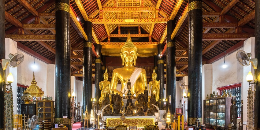 A picture of tourists at Wat Traimit, following temple etiquette and admiring the Buddha.