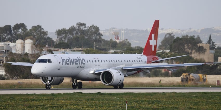 Aeroplane getting ready to take off on the runway with a red tail and white body