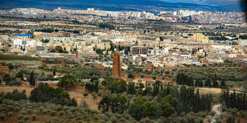 An aerial view of a city in Algeria with lush green forests and parks visible around