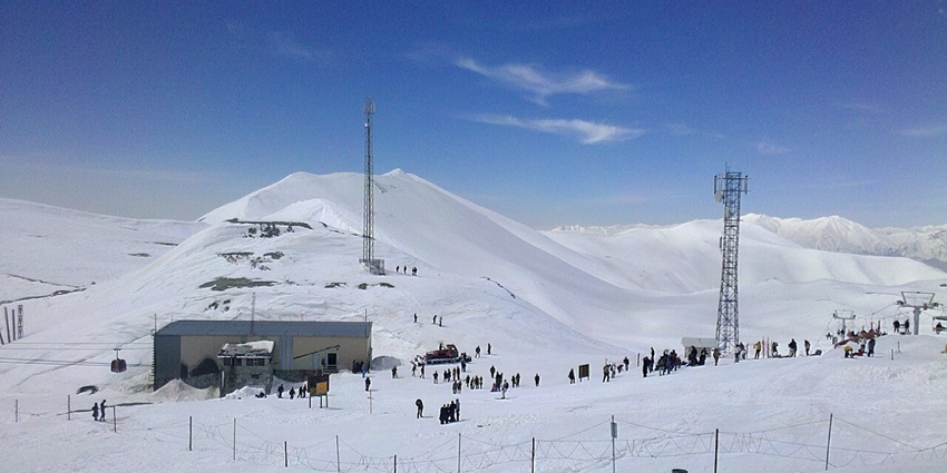 Tochal sports complex with cable cars, mountain backdrop, and clear blue sky above