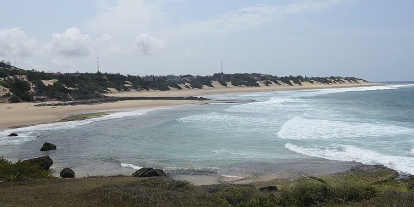 Tofo Beach with a clear blue water body, sandy shorelines and distant tall towers