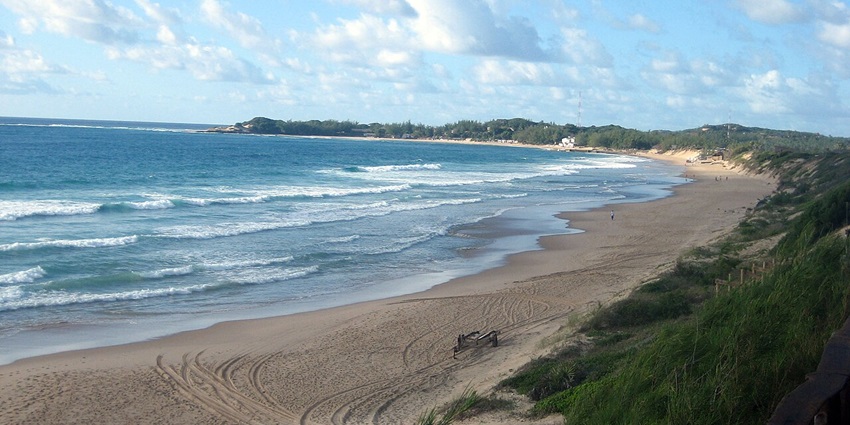 Tofo with distant buildings, tofo sea on the side and greenery on the other side