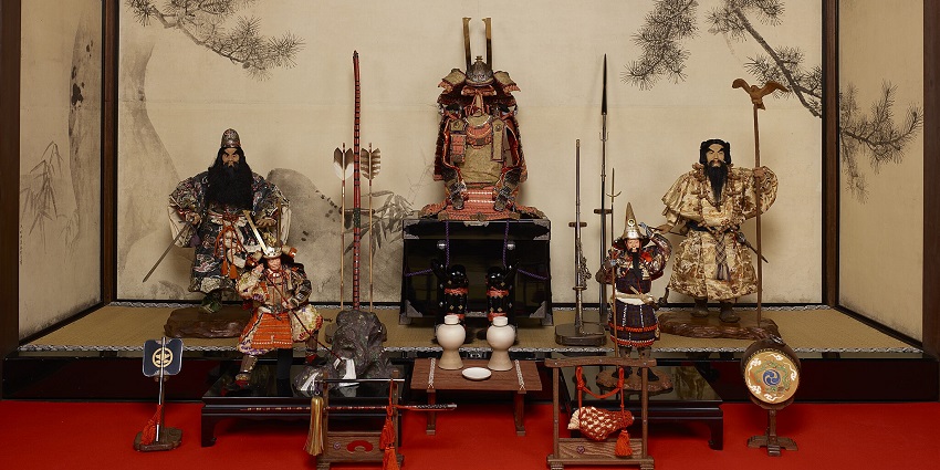 View of traditional Japanese samurai armour displayed alongside weapons in a room.