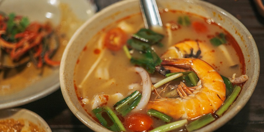 An image of the spicy and sour Thai soup with shrimps, lemongrass, and lime on it