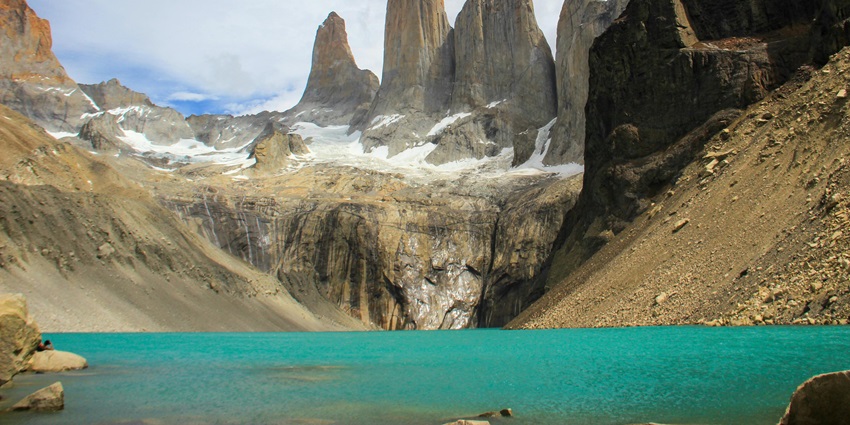 An image of a river reflecting snowy peaks at the W Trek in Patagonia, surrounded by hills.