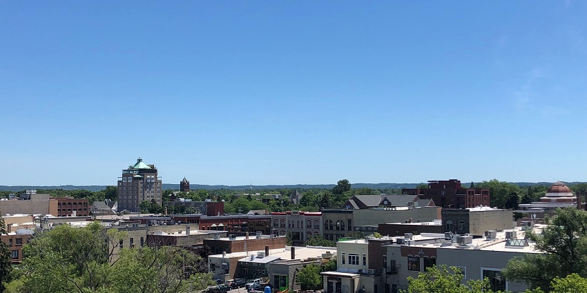 Traverse city from above with multiple buildings, houses, greenery and vehicles parked.