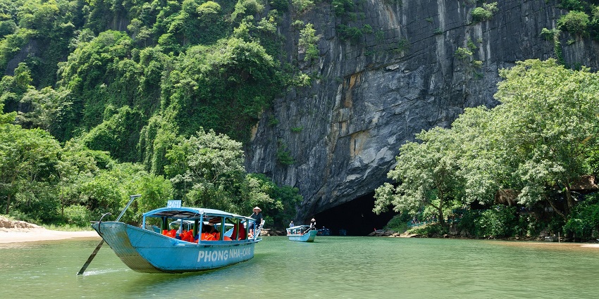 An image showing a boat on a river near a cave entrance, similar to Trinh Nu (Virgin) Cave