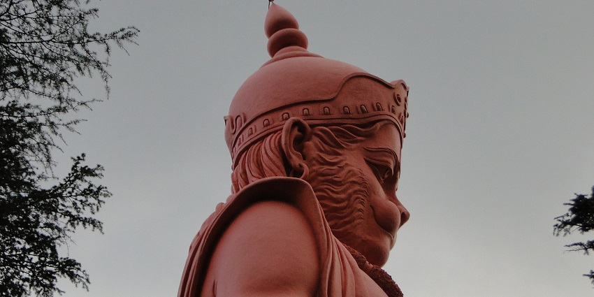 A sideways picture of a tall statue of Lord Hanuman at a temple in Faridabad