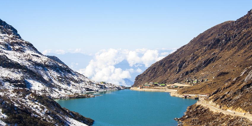 Tsongmo Lake’s surface reflects surrounding misty, peaks, creating a surreal view.