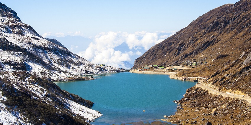 Tsomgo Lake with a clear water body, sandy shores on one side and snow-covered mountains