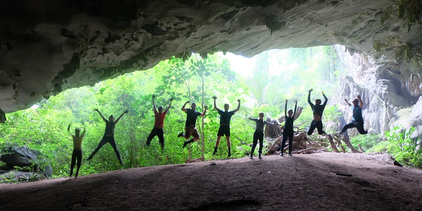 An image of Tu Lan Cave System in Vietnam, featuring a river, lush greenery, and rugged rock formations.