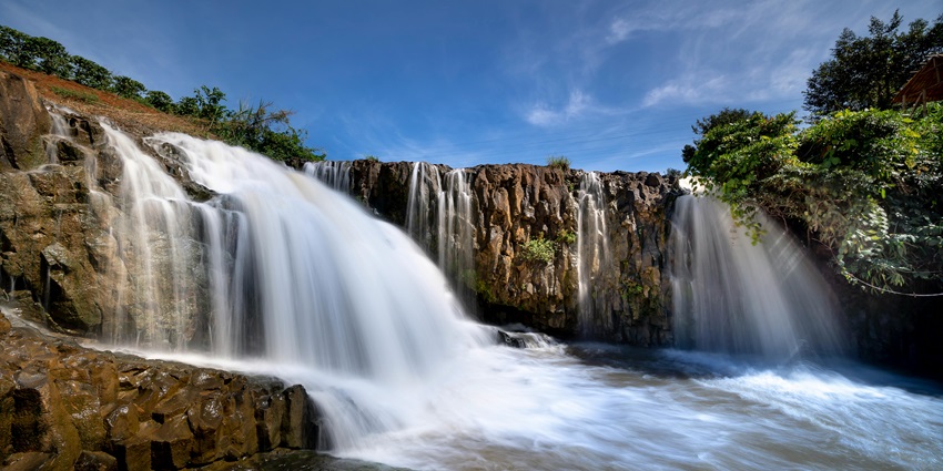 Tukad Cepung Waterfall cascades through a narrow canyon, where sunlight streams through the rocky openings, creating mesmerizing light rays.