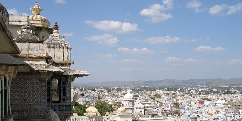 Udaipur City Palace’s ornate white-and-pastel turrets and domes at dusk against a soft Rajasthan sky