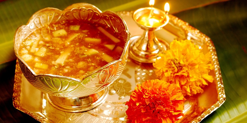 An image of a traditional Indian offering with a bowl of food, flowers, and a lit lamp 0 different harvest festivals in India