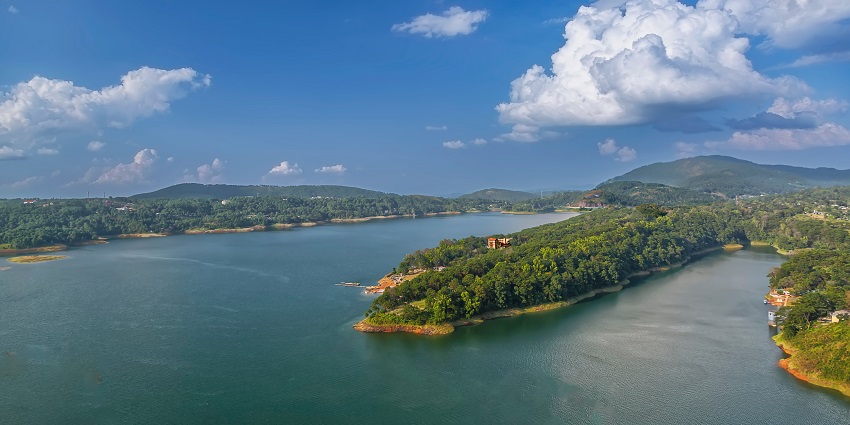 Umiam Lake with a peaceful water surface surrounded by lush green mountains under the clear sky