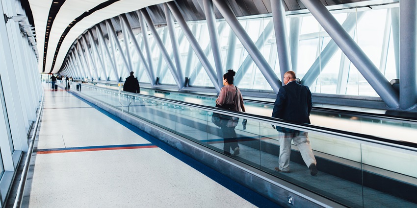 People are walking along a moving walkway in the terminal at one of the airports in Bolivia.