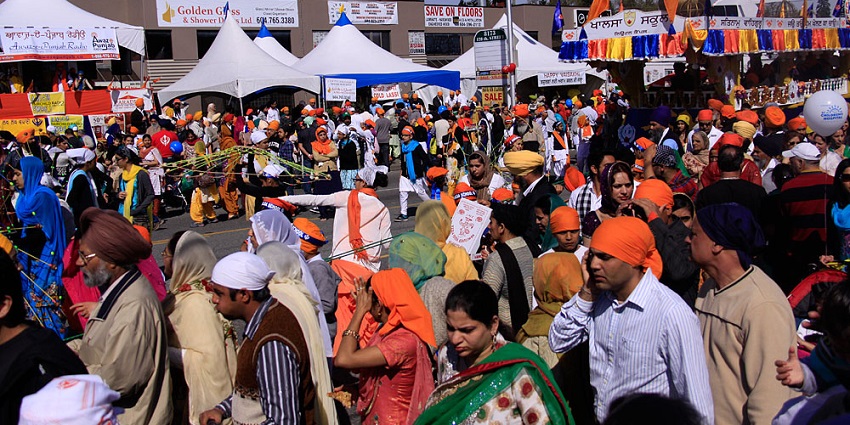 An image of a group of men in white kurta pajamas with bright orange turban, celebrating the Vaisakhi festival