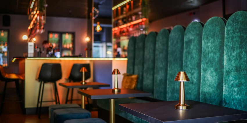 The stylish cocktail bar glows with warm lighting, plush seating, and a cosy ambience.