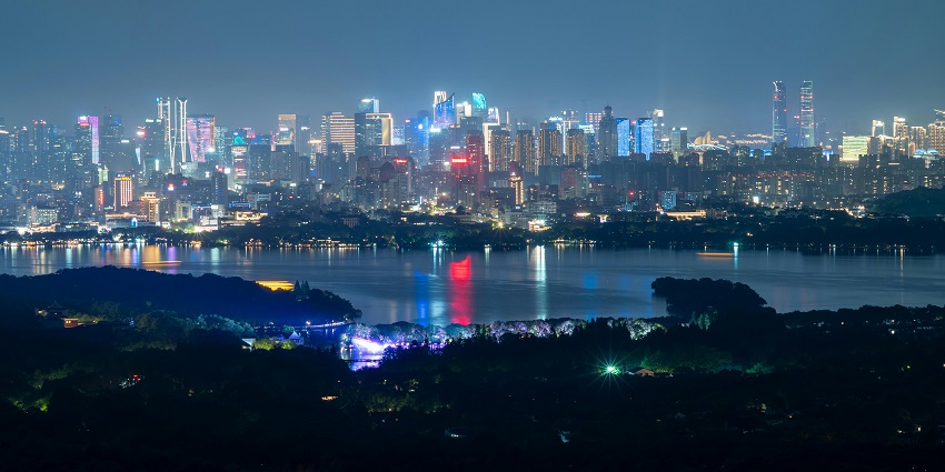 Distant buildings beyond a lake illuminated with colourful lights in the city at night