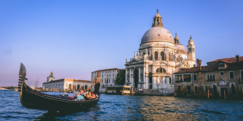 A picturesque Venetian canal with boats and historic architecture in the evening glow.