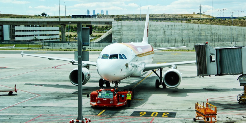 A commercial airplane docking at the gate while the ground crew is preparing for departure