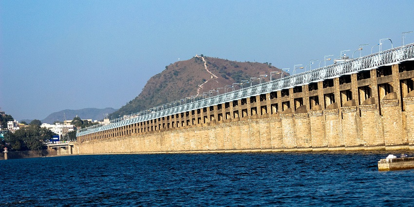 Clear blue water near the Prakasham Barrage in Vijayawada, with a backdrop of a mountain.