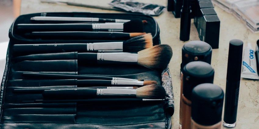 A makeup brush set with foundation, lipstick, and beauty essentials on a vanity table.