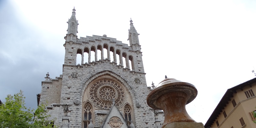 A historic church is standing tall while a fountain is elegantly flowing in the foreground.