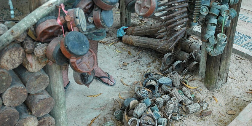 An image of the Cambodia Landmine Museum, with a display of bombs, shells in cages, buildings.