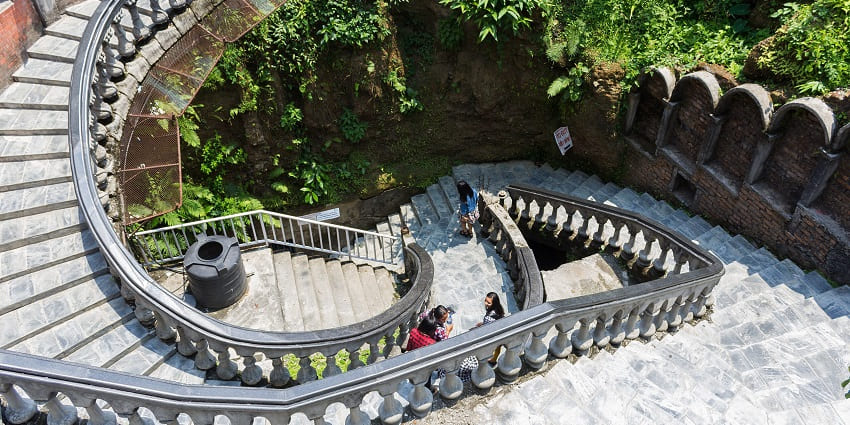 Stone stairs lead the way into Gupteshwor Cave, surrounded by rugged rock formations
