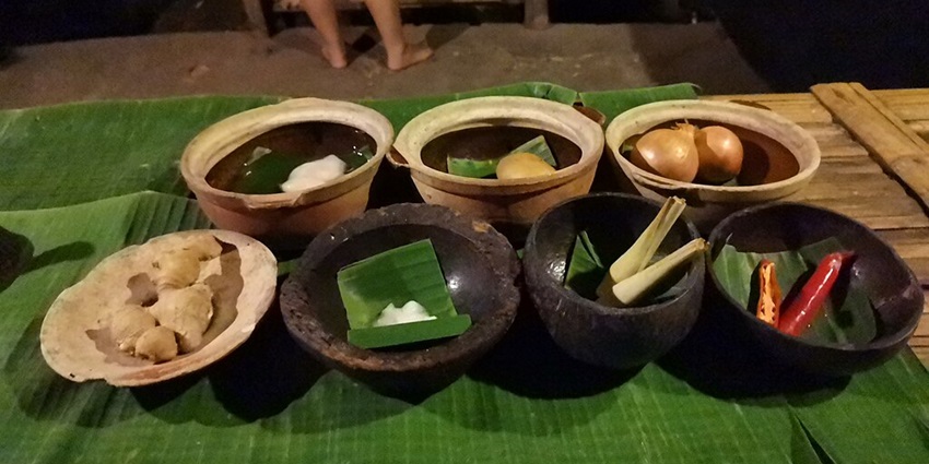 An image of fresh ingredients on a green banana leaf: coconut cream, ginger, lemongrass