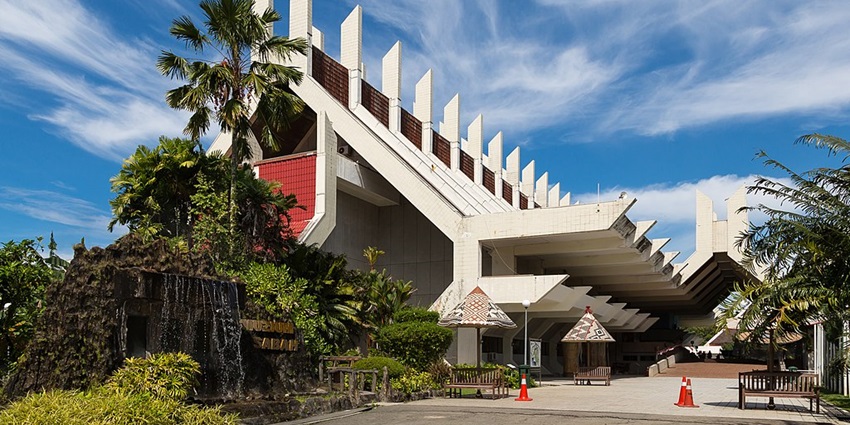 An image of a modern Sabah Museum building with white panels, palm trees