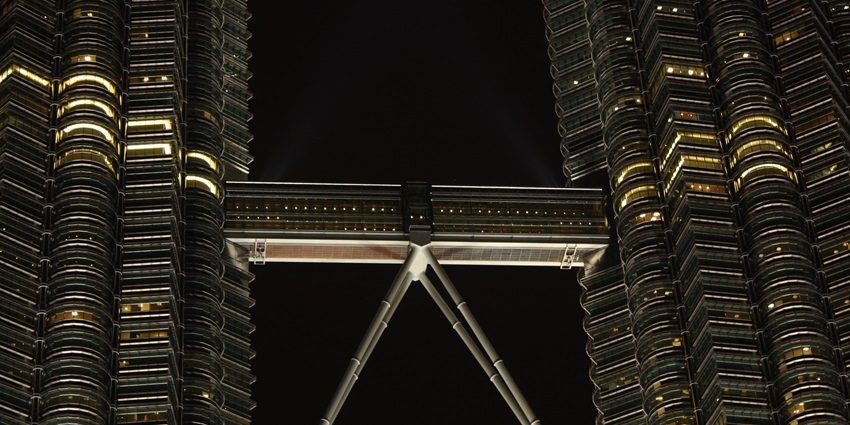 Skybridge of Petronas Twin Towers, illuminated at night, showcasing modern architecture.