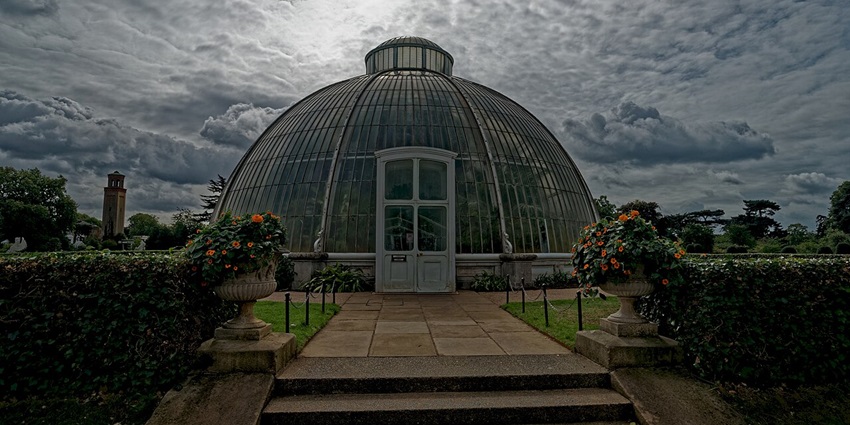 Glasshouse walkway at Kew Gardens, leading toward the historic Palm House under glass.