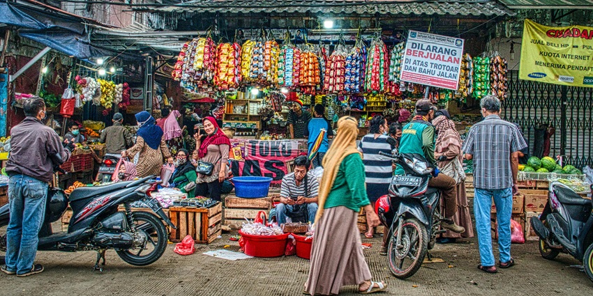 Shoppers explore a bustling outdoor market lined with colorful stalls and local vendors during daytime, one of the best things to do in Pekanbaru.