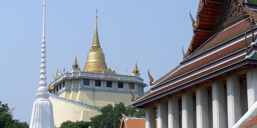 An image of Wat Saket in Bangkok, a hilltop golden temple surrounded by an abundance of lush greenery.